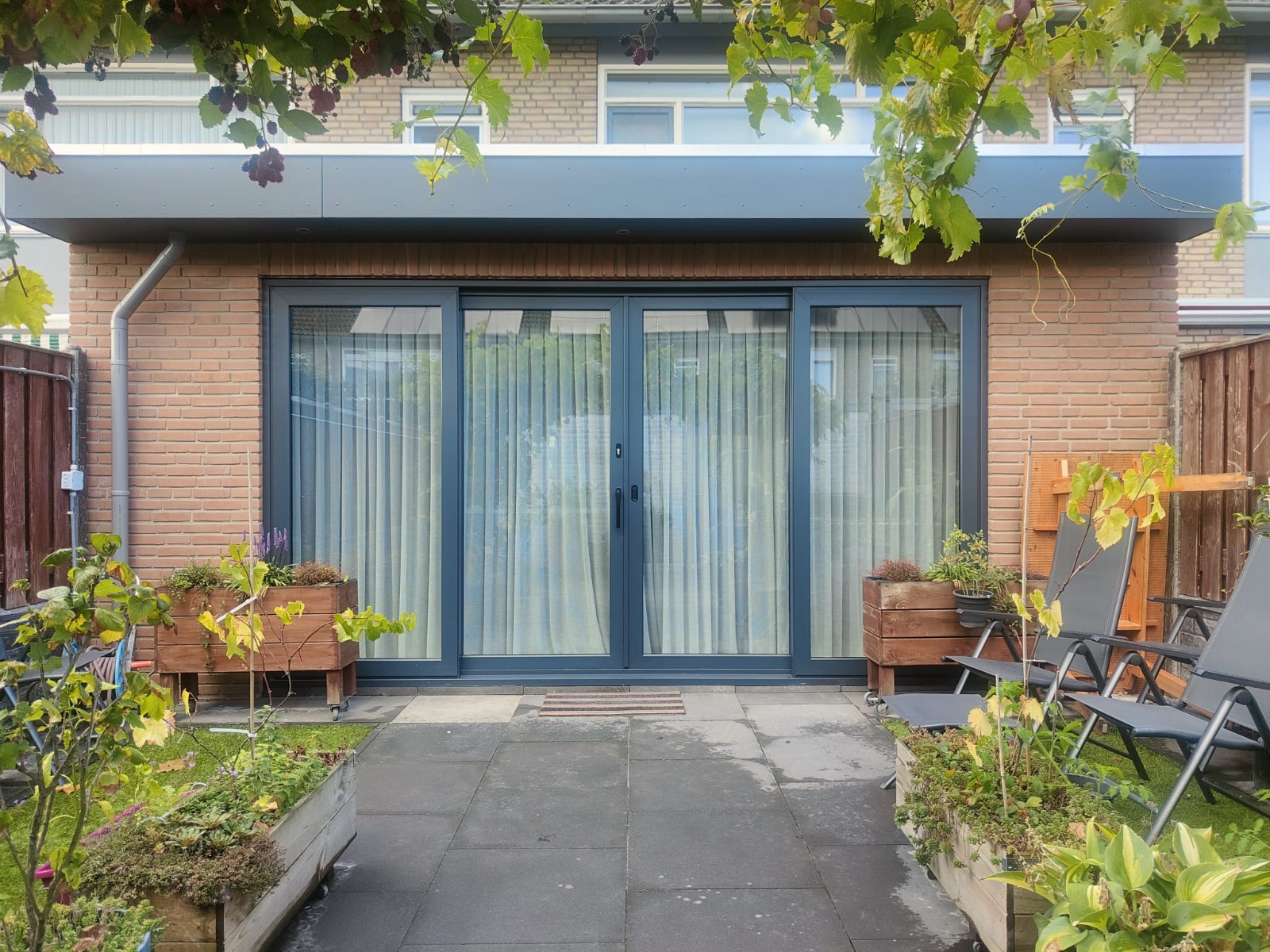 Rear home extension with grey sliding patio doors in Geldrop